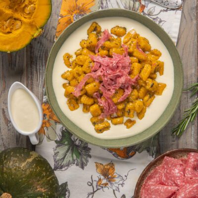 Gnocchi di zucca alle erbe su fonduta di formaggio con julienne di salame croccante