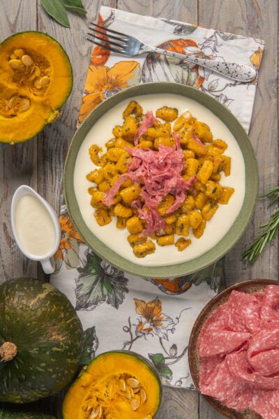 Gnocchi di zucca alle erbe su fonduta di formaggio con julienne di salame croccante