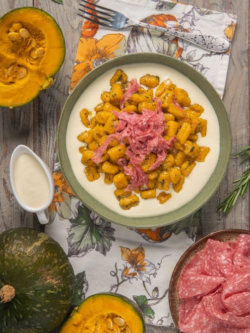Gnocchi di zucca alle erbe su fonduta di formaggio con julienne di salame croccante
