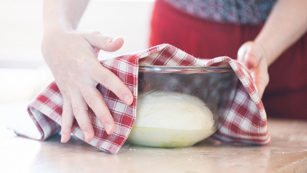 Impasto per pizza coperto con un canovaccio a quadri per la lievitazione