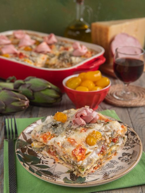 Lasagne con carciofi, mortadella e pomodorini gialli gratinate con parmigiano, servite a fetta