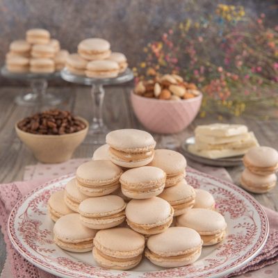 Macarons al caffè impilati a piramide su piatto decorato con farcitura color caramello