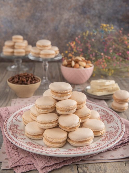 Macarons al caffè impilati a piramide su piatto decorato con farcitura color caramello