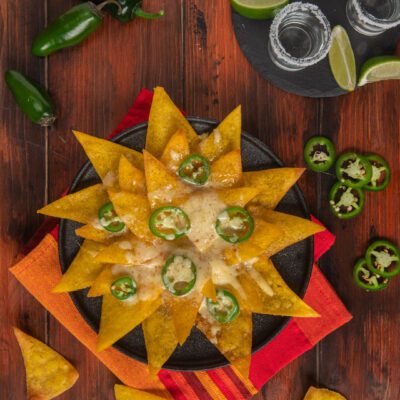 Nachos con formaggio fuso e rondelle di jalapeño disposti a raggiera in padella di ferro
