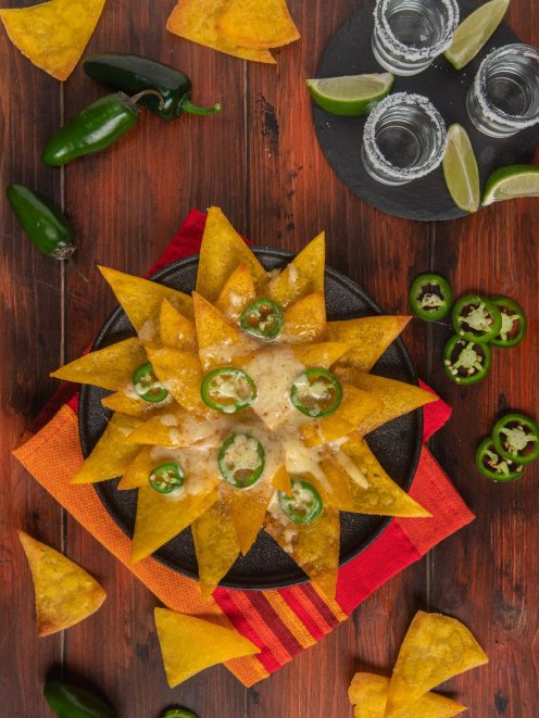 Nachos con formaggio fuso e rondelle di jalapeño disposti a raggiera in padella di ferro
