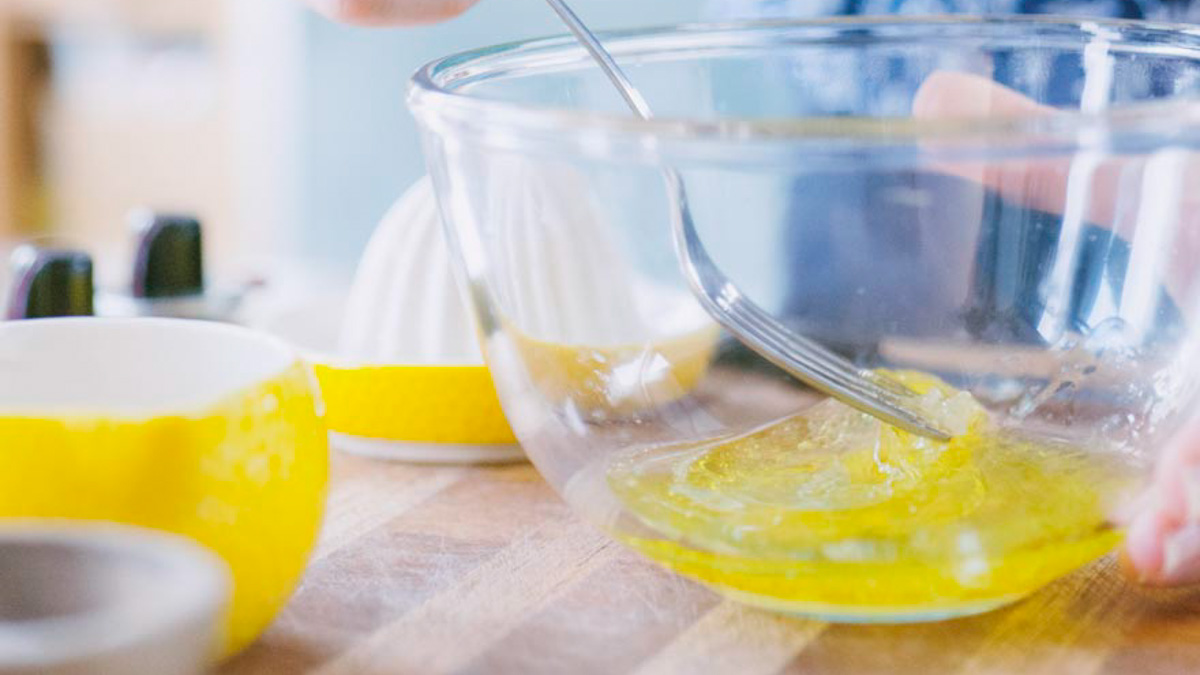 Uova sbattute con una frusta in una ciotola di vetro per preparare un'emulsione cremosa