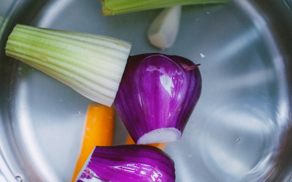 Cipolla rossa, sedano, carota e aglio in acqua fredda pronti per il brodo di cottura