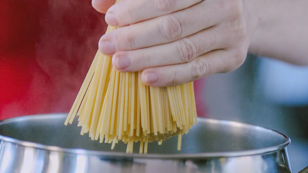 Pentola con acqua che bolle e spaghetti pronti per la cottura