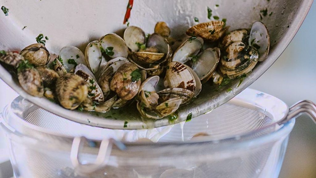 Vongole scolate e sgusciate accanto ad altre ancora col guscio per gli spaghetti alle vongole