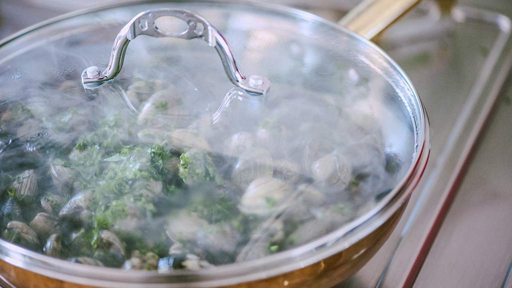 Vongole che si schiudono in padella con i gusci aperti durante la cottura