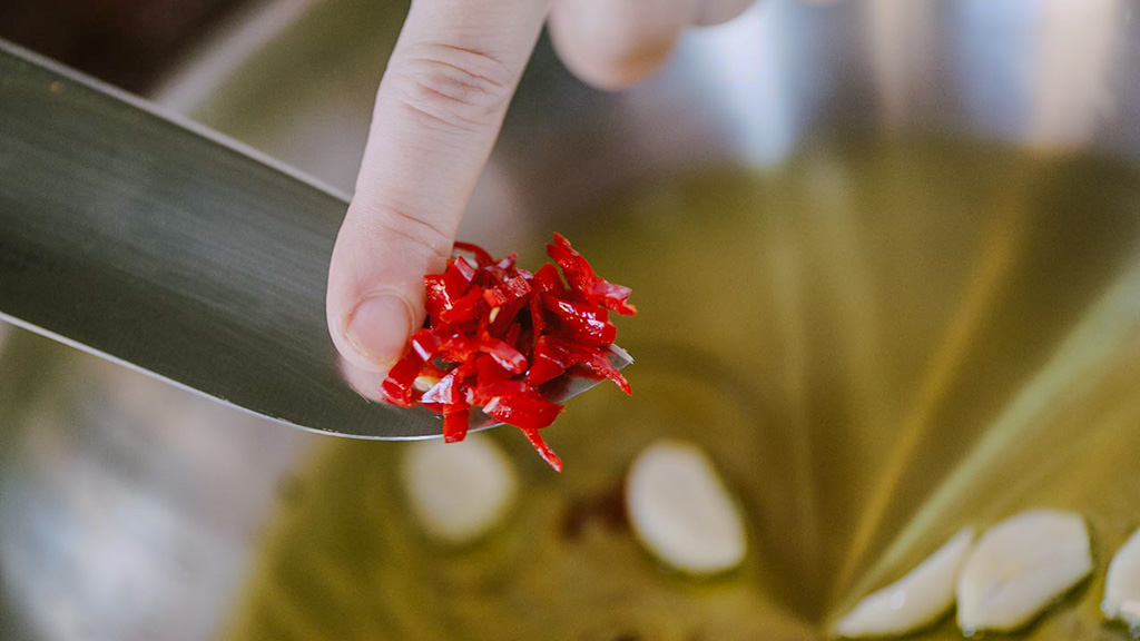 Aglio e peperoncino che soffriggono nell'olio con gambi di prezzemolo profumati