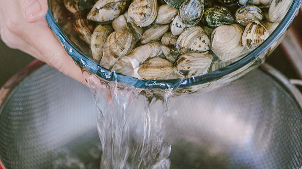 Vongole in ammollo in acqua fredda e sale grosso per eliminare la sabbia