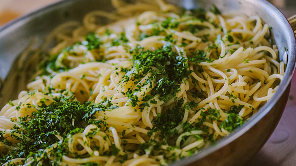 Spaghetti alle vongole impiattati con vongole sgusciate, prezzemolo fresco e un filo d'olio a crudo