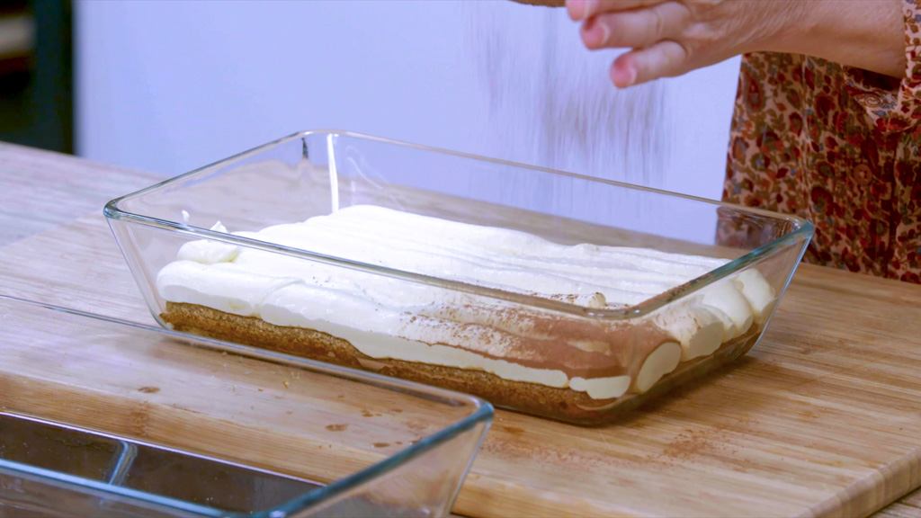 Strato di crema al mascarpone coperto di cacao amaro setacciato sul tiramisù