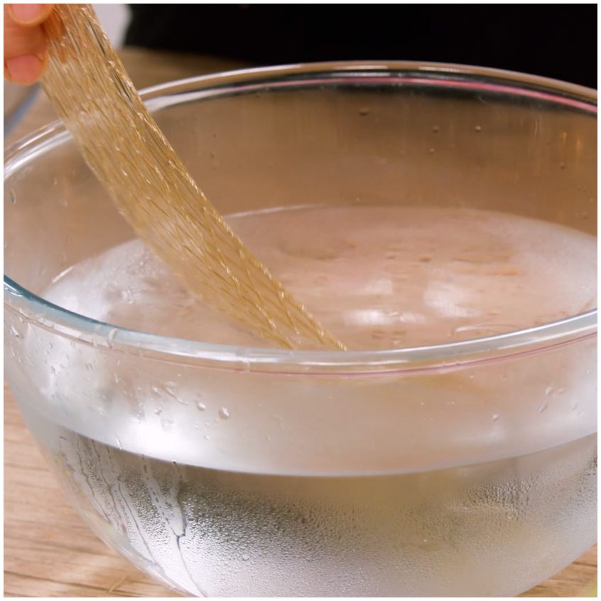 Fogli di gelatina immersi in acqua fredda per reidratarsi in una ciotola