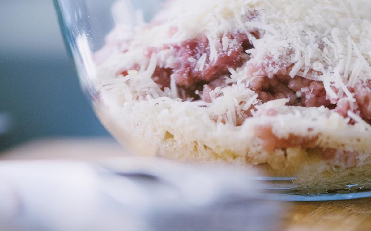 Composto di carne macinata e pane ammollato cosparso di formaggio grattugiato, pronto da impastare