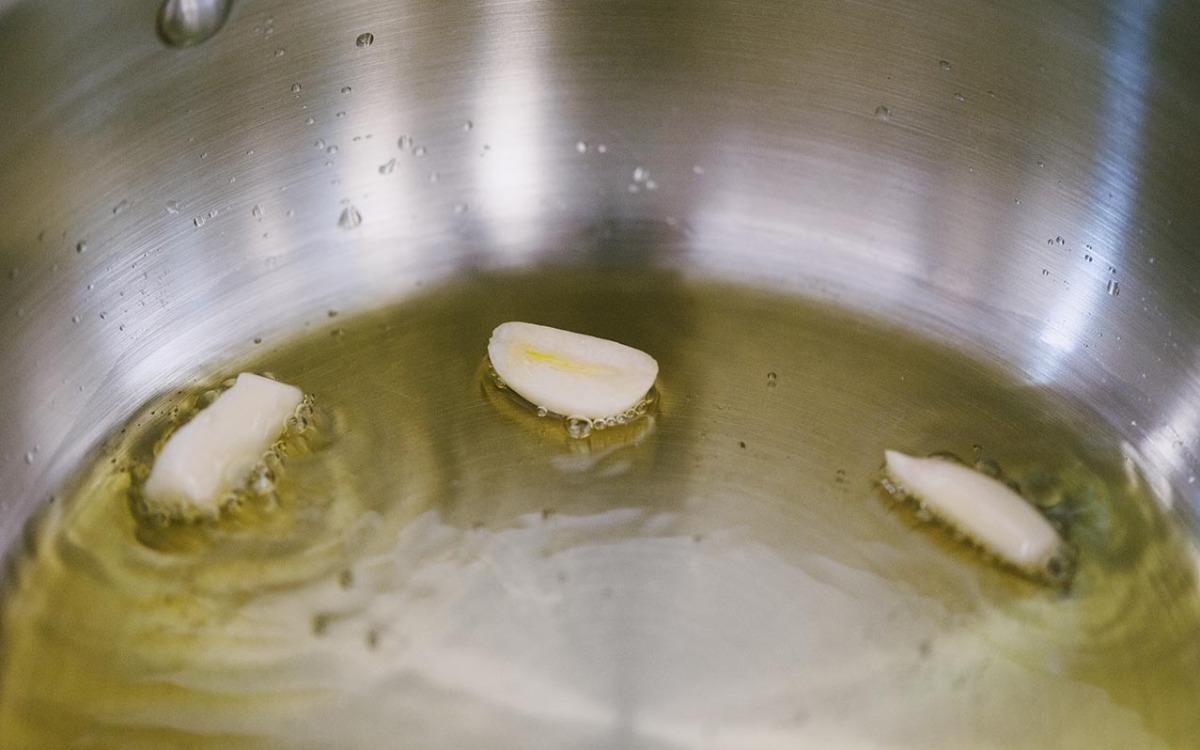 Spicchi d'aglio che soffriggono nell'olio extravergine in casseruola