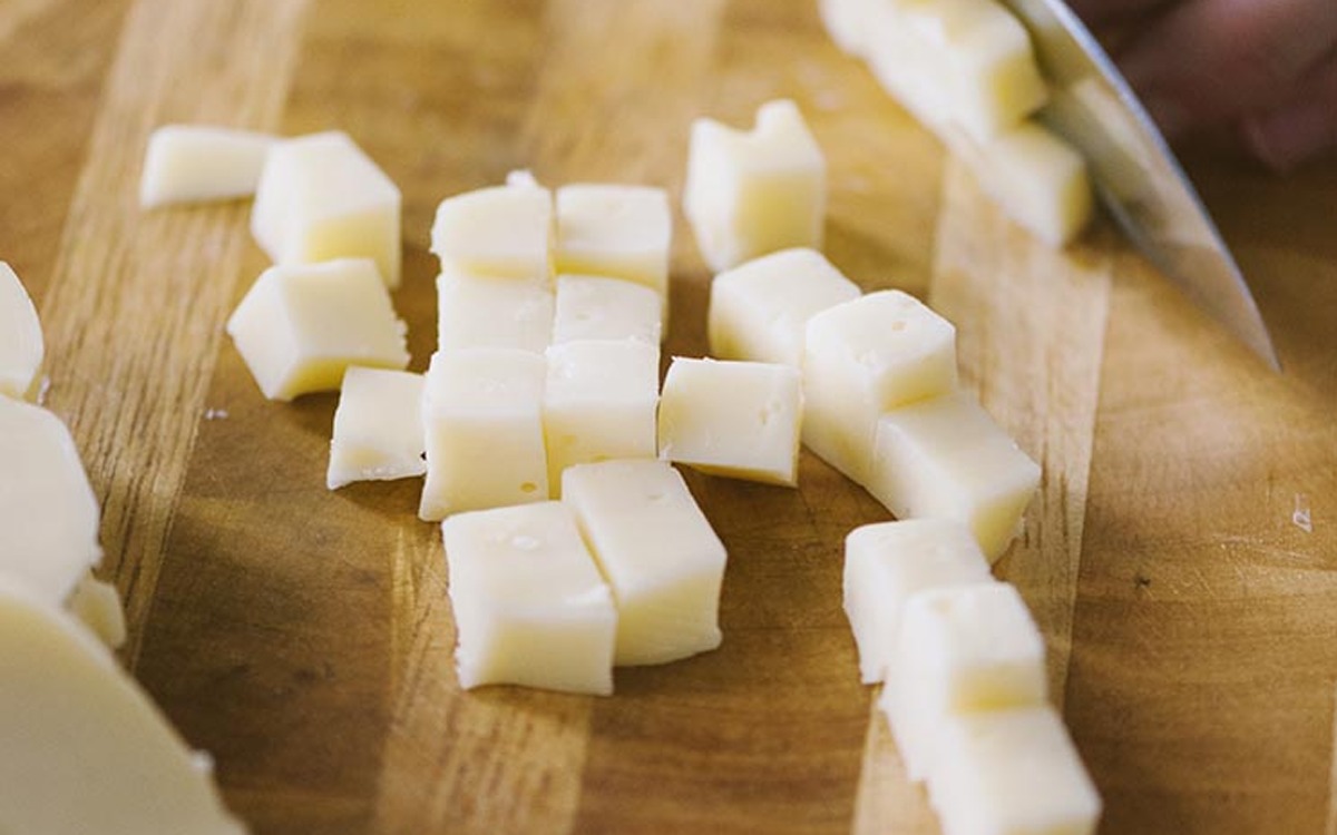 Cubetti di scamorza tagliati a coltello sul tagliere, pronti per la pasta al forno