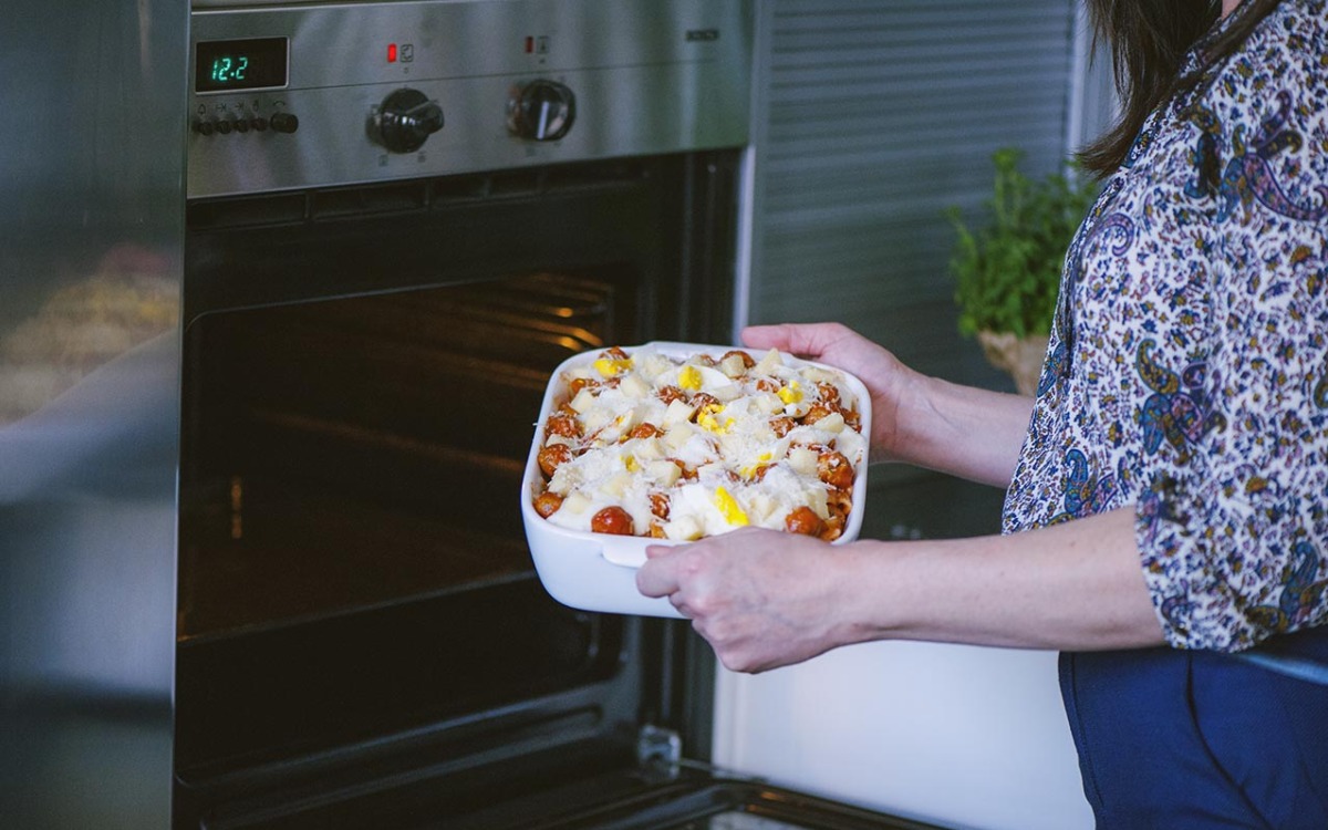 Teglia di pasta al forno con pomodorini, mozzarella e formaggio grattugiato infornata