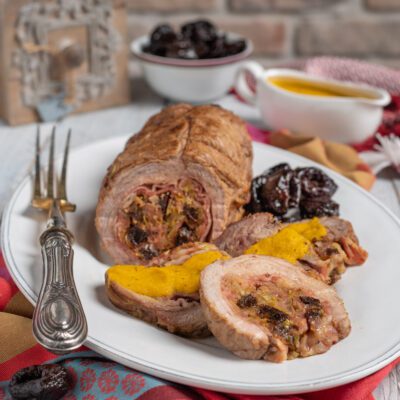 Arrosto ripieno con prugne affettato, servito con salsa allo zafferano e prugne caramellate