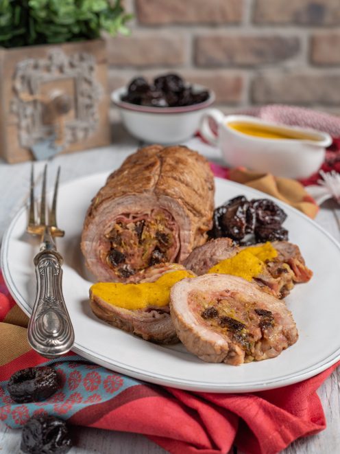 Arrosto ripieno con prugne affettato, servito con salsa allo zafferano e prugne caramellate
