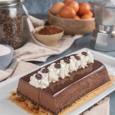 Bonet al caffè a forma di plumcake con glassa lucida, ciuffi di panna e chicchi di caffè