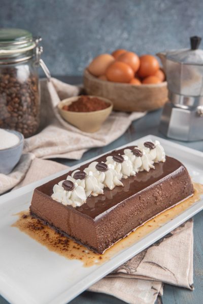 Bonet al caffè a forma di plumcake con glassa lucida, ciuffi di panna e chicchi di caffè