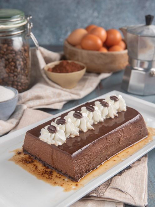 Bonet al caffè a forma di plumcake con glassa lucida, ciuffi di panna e chicchi di caffè