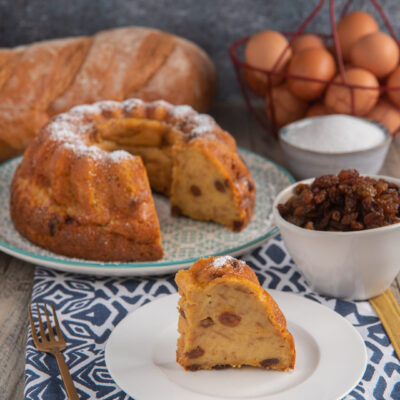 Budino di pane a ciambella con uvetta, spolverato di zucchero a velo, servito a fette