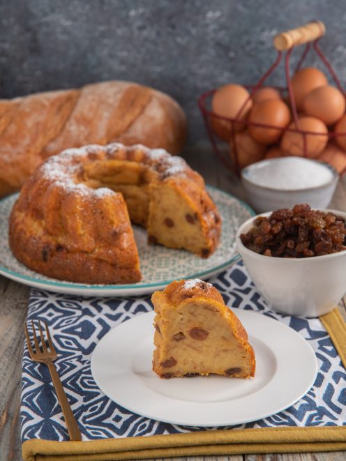 Budino di pane a ciambella con uvetta, spolverato di zucchero a velo, servito a fette