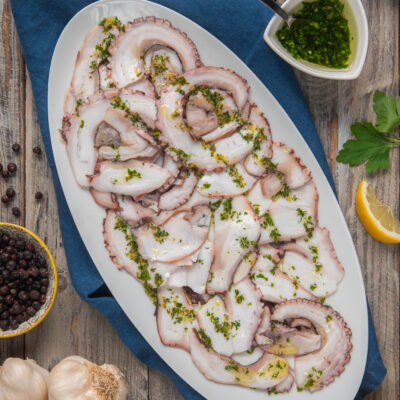Carpaccio di polpo affettato finemente con gremolata di prezzemolo e aglio