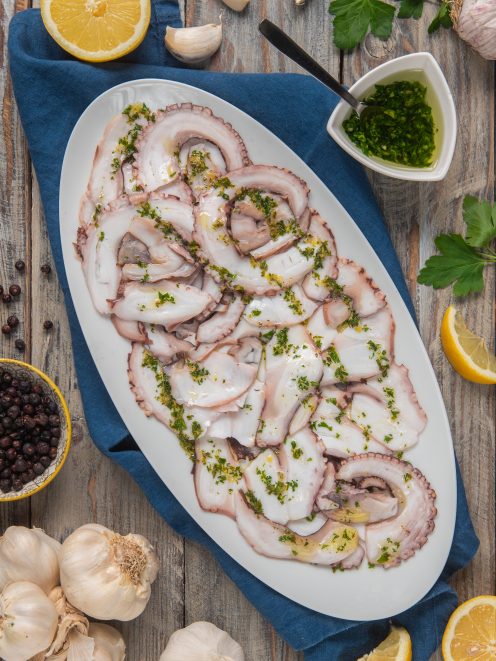Carpaccio di polpo affettato finemente con gremolata di prezzemolo e aglio
