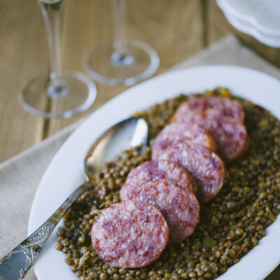 Cotechino con lenticchie servito a fette su un letto di lenticchie in umido