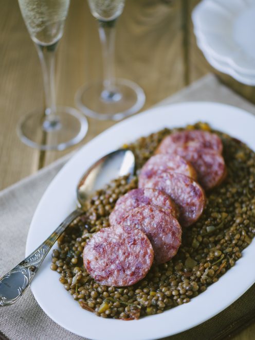 Cotechino con lenticchie servito a fette su un letto di lenticchie in umido