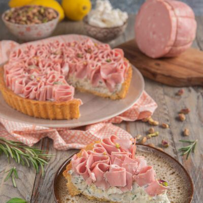 Crostata salata con ricotta e mortadella affettata a rose, con pistacchi, servita a fette