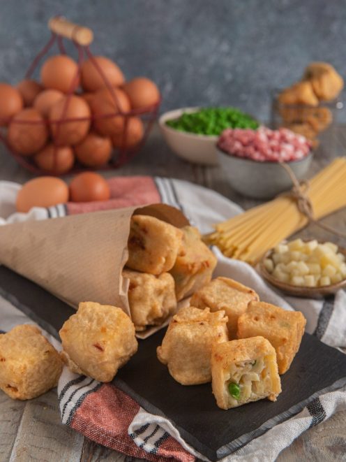 Frittatine di pasta alla napoletana fritte e dorate, una spezzata mostra il ripieno con piselli e prosciutto