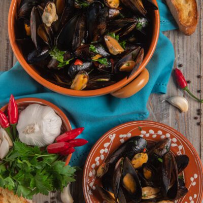 Impepata di cozze con prezzemolo e peperoncino, servita con fette di pane tostato