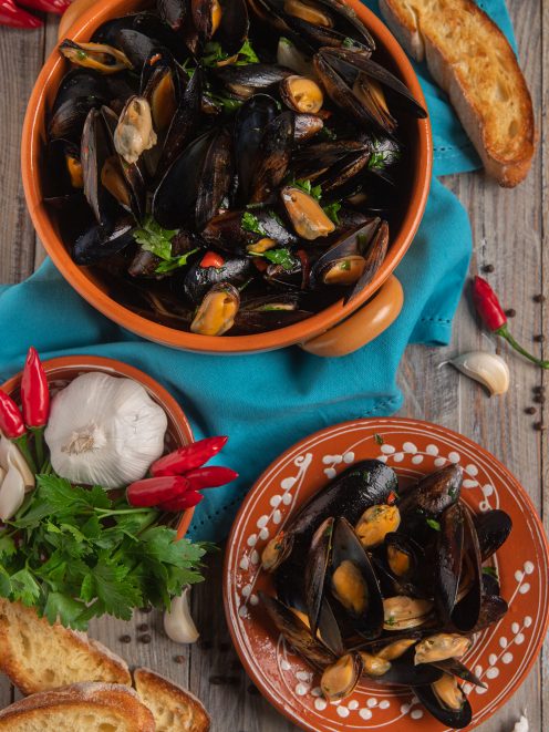 Impepata di cozze con prezzemolo e peperoncino, servita con fette di pane tostato