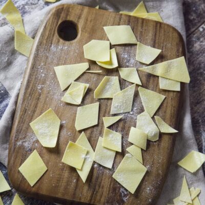 Maltagliati freschi all'uovo tagliati a losanga, spolverati di farina su un tagliere