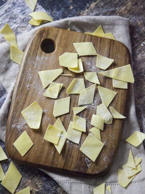 Maltagliati freschi all'uovo tagliati a losanga, spolverati di farina su un tagliere