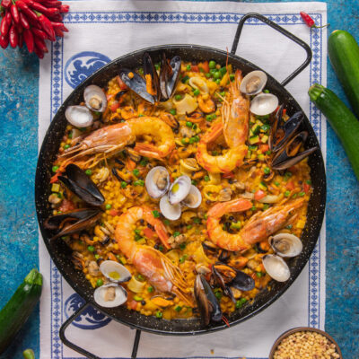 Paella di fregola ai frutti di mare con gamberi interi, cozze aperte, vongole e piselli