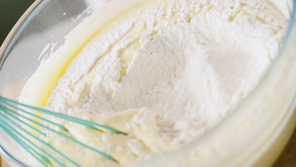Farina e fecola setacciate incorporate nel composto con spatola, movimento dal basso verso l'alto