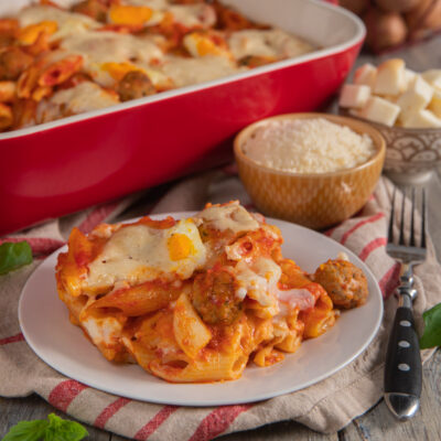 Pasta al forno con polpette, sugo di pomodoro e mozzarella filante servita nel piatto