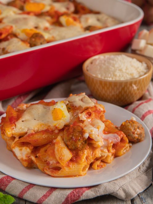Pasta al forno con polpette, sugo di pomodoro e mozzarella filante servita nel piatto