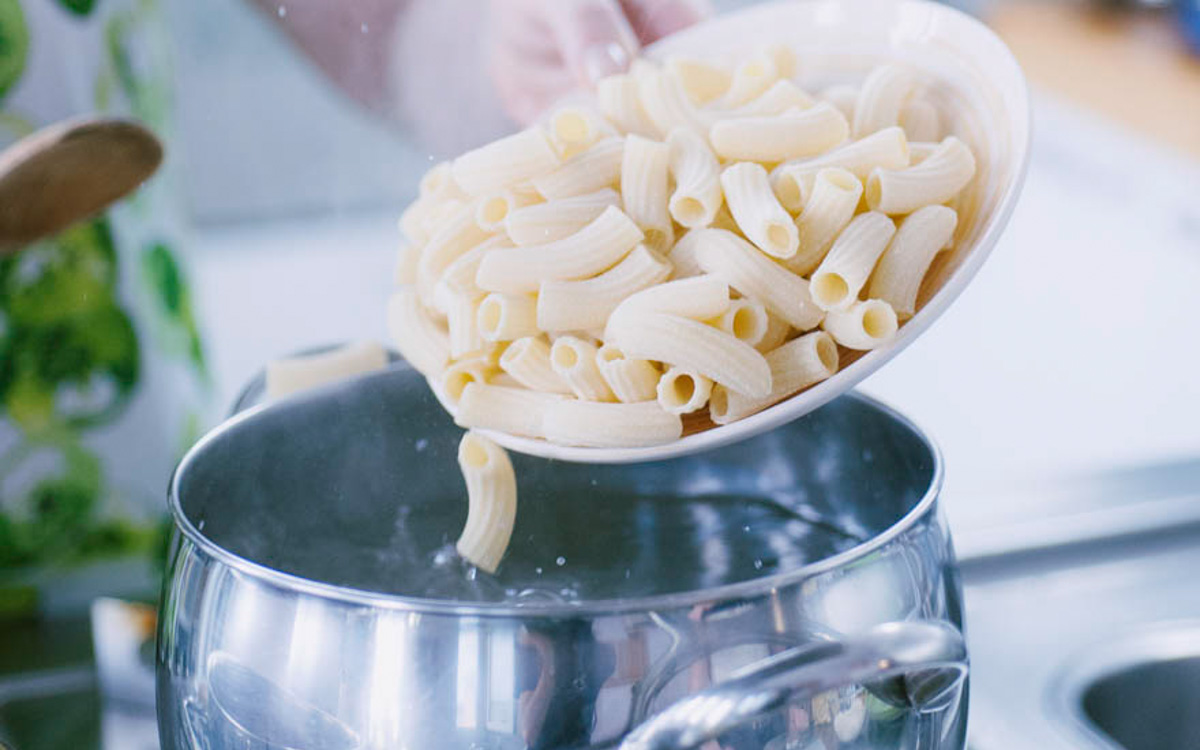 Tortiglioni cotti versati nell'acqua bollente per la pasta alla norma