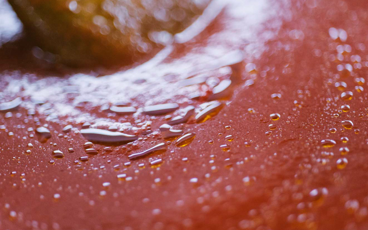 Sugo di pomodoro che sobbolle con gocce di olio in superficie e un cucchiaio che mescola
