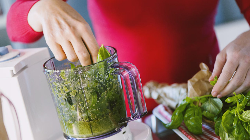 Foglie di basilico e pinoli frullati con olio extravergine per il pesto alla genovese