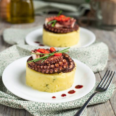 Tortino di patate con polpo grigliato, peperoncino fresco ed erba cipollina su riduzione al vino rosso