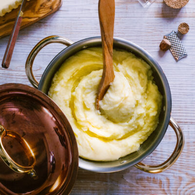 Purè di patate cremoso con burro fuso che cola sulla superficie, servito in pentola