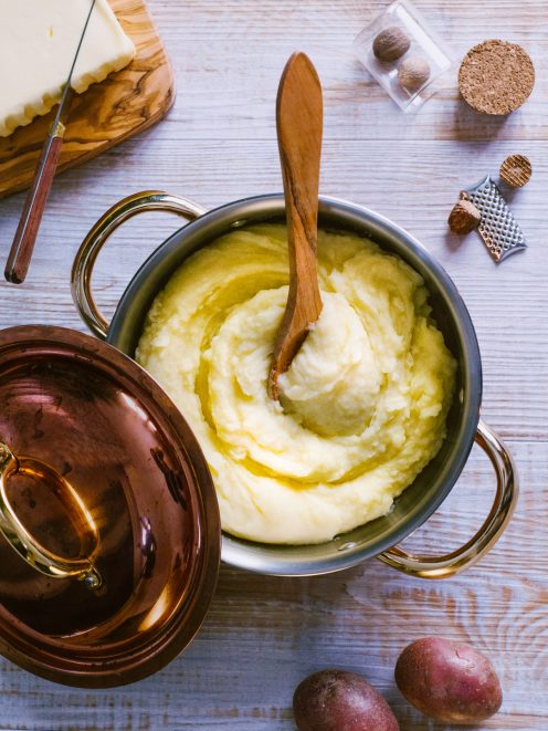 Purè di patate cremoso con burro fuso che cola sulla superficie, servito in pentola